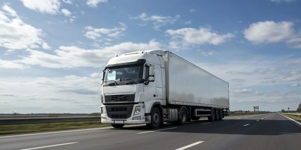 white-semi-truck-driving-highway-blue-sky